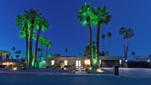 A residential property with a driveway, palm trees, and a well-lit entrance. - Palm Springs Retreat-Come and relax. (Palm Springs)