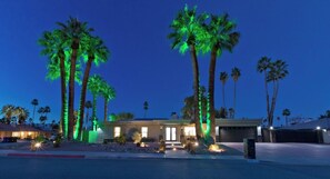 A residential property with a driveway, palm trees, and a well-lit entrance. - Palm Springs Retreat-Come and relax. (Palm Springs)