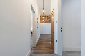Ein Flur mit Holzboden, weißen Wänden und einer Wand in Backsteinoptik.