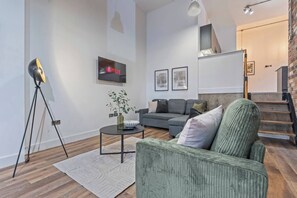Ein modernes Wohnzimmer mit einem grauen Sofa, einem Couchtisch und einer Stehlampe.