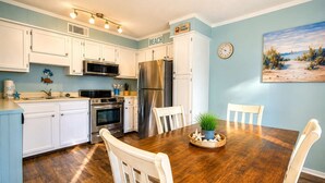 Una cocina con armarios blancos, electrodomésticos de acero inoxidable y una mesa de comedor con sillas.
