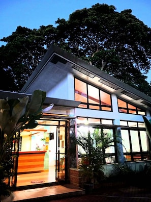 A modern building with large windows and a well-lit interior. - Julieta Pension House (Puerto Princesa)