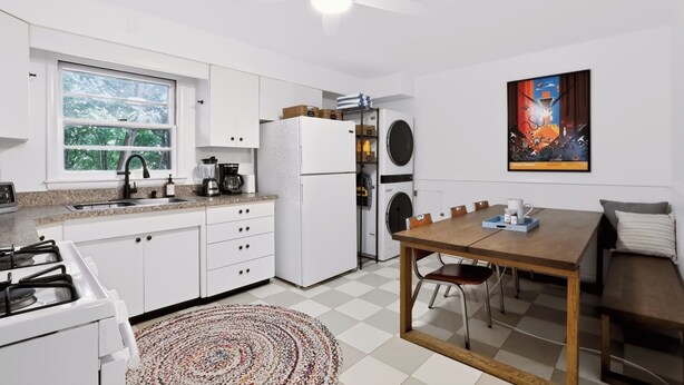 A compact kitchen with a gas stove, a refrigerator, a built-in oven, and a window with a view of greenery. - Close to campus. Awesome hangout home! (Bloomington)