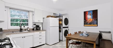 A compact kitchen with a gas stove, a refrigerator, a built-in oven, and a window with a view of greenery.