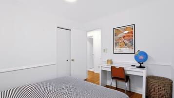 Een kamer met een bed, een bureau, een stoel, een wereldbol en een lijst met een afbeelding aan de muur.