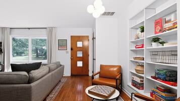 Una sala de estar con un sofá, una mesa de centro, una estantería y una puerta.