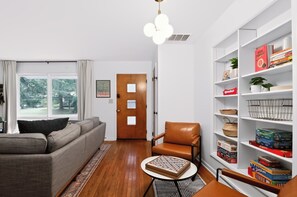 Una sala de estar con un sofá, una mesa de centro, una estantería y una puerta.