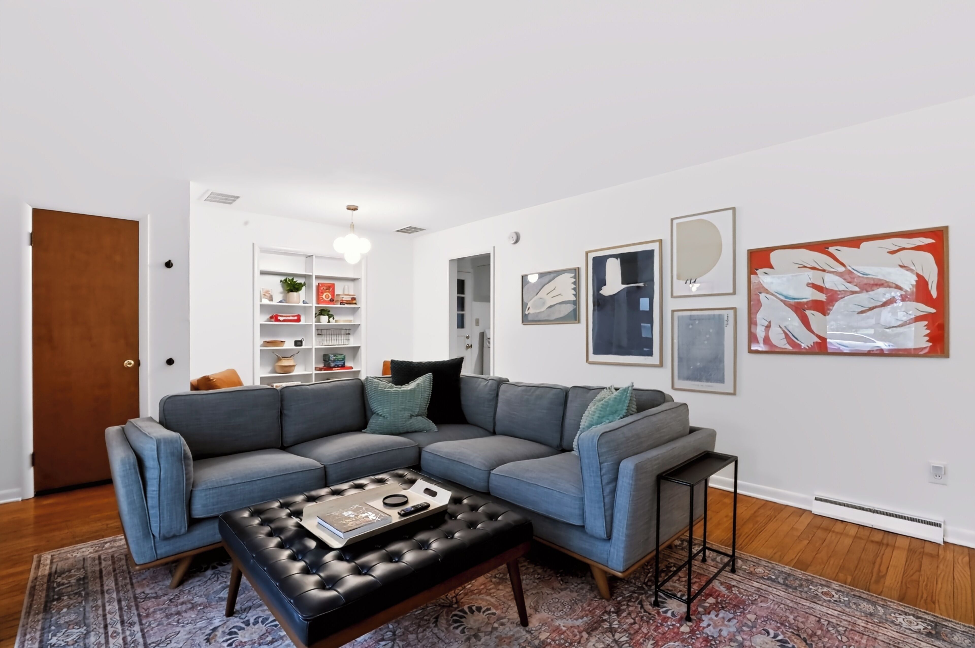 A modern living room with a sectional sofa, a coffee table, and a bookshelf.