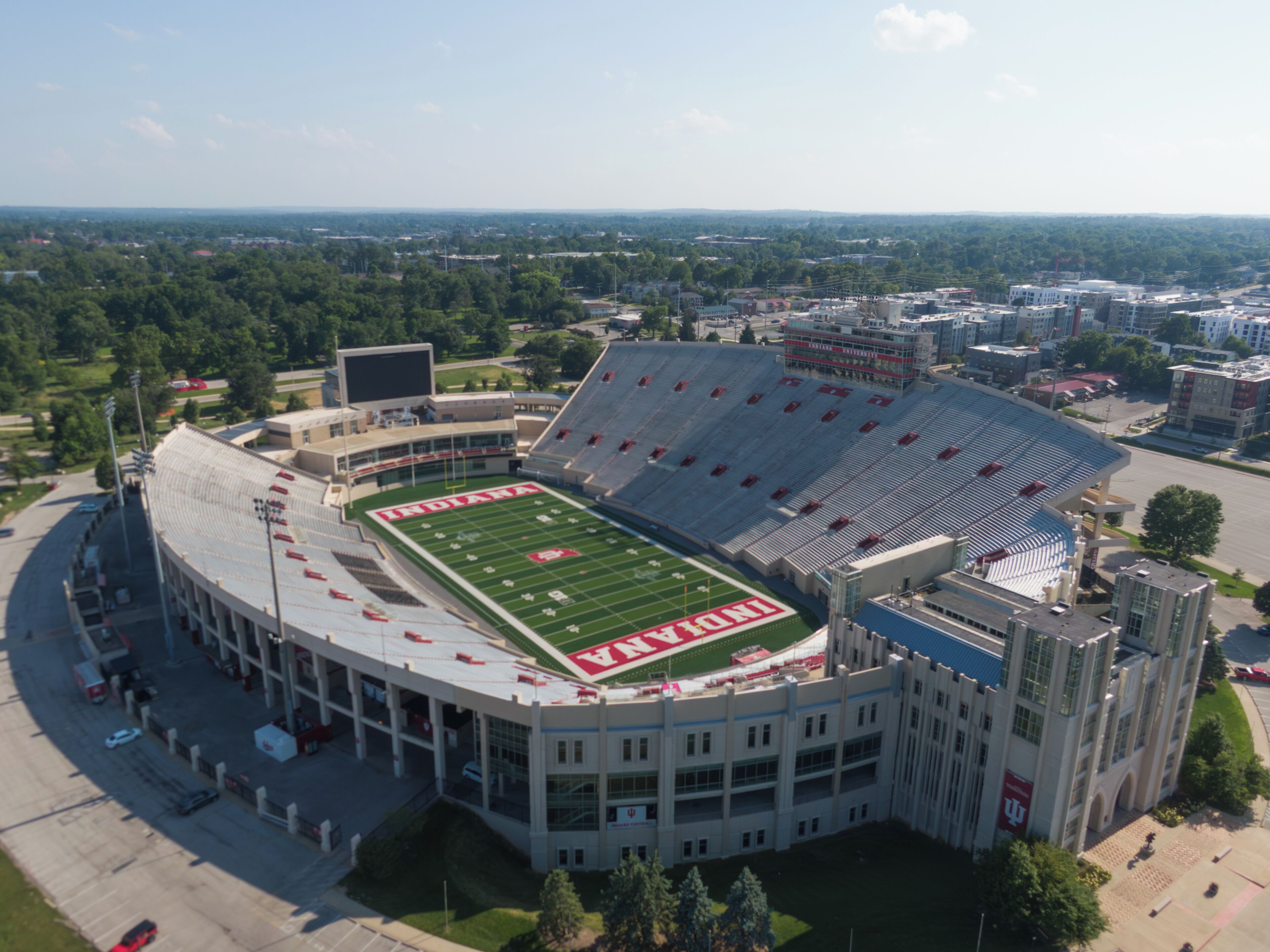 A large stadium with a football field, surrounded by parking areas and buildings.
