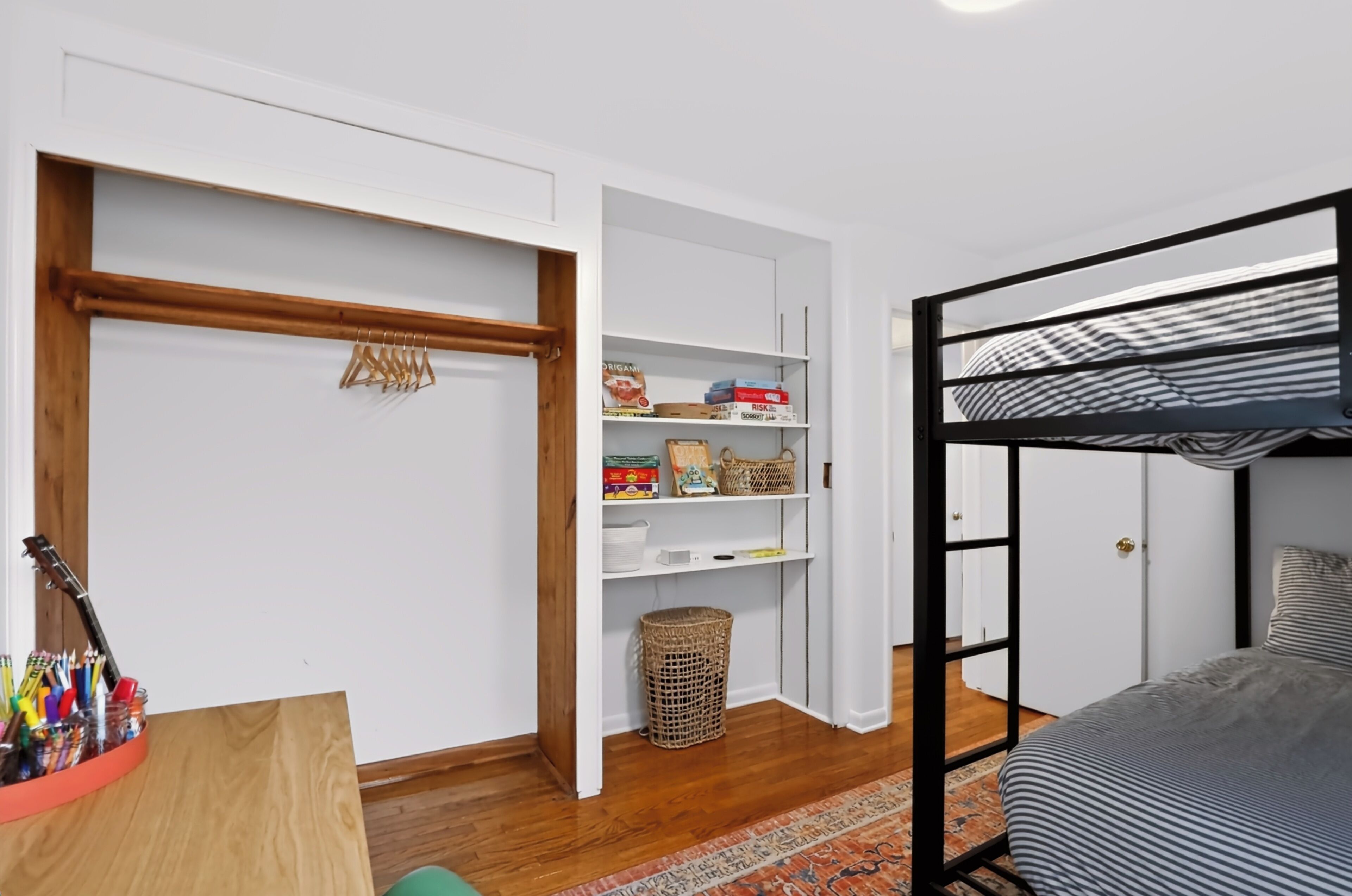 A room with a bunk bed, a wooden door, a white closet, and a shelf with various items.
