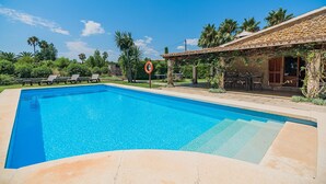 A clear blue swimming pool with lounge chairs and a lifebuoy sign, surrounded by greenery and a stone building. - Elegant Pool Villa in Alcudia (Alcúdia)