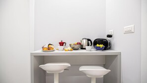 Eine Küchenarbeitsplatte mit Kaffeemaschine, Wasserkocher und Schalen mit Obst.