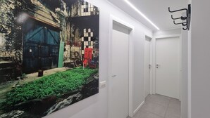 Un pasillo con un mural que representa una escena industrial, una puerta blanca y un gancho fijado en la pared.