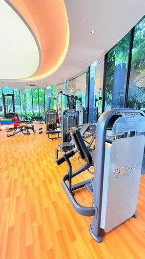 Ein Fitnessraum mit Trainingsgeräten, großen Fenstern und Holzboden.