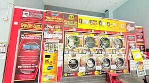 Eine Waschsalon mit mehreren Waschmaschinen, Werbeschildern und einem roten Hocker.