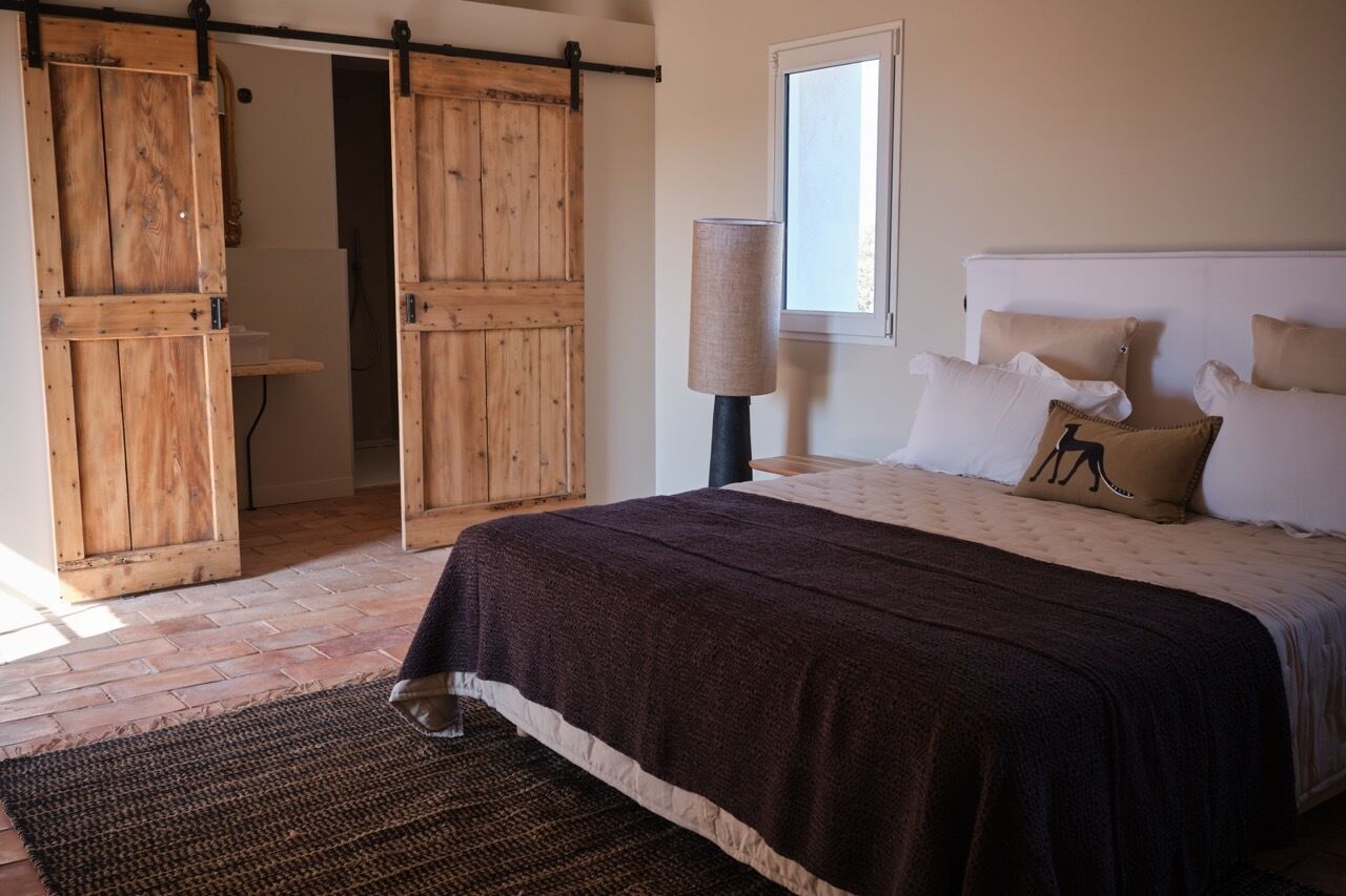 Een slaapkamer met een bed, een raam en een houten deur.