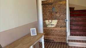 A hallway with a wooden bench, a patterned floor, a rustic wall with a hanging bag, and a staircase. - Farmhouse in Provence (Pernes-les-Fontaines)