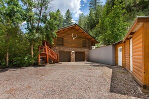 A log cabin with a stone foundation, a wooden porch, and a garage.