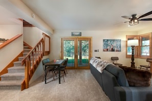 A living room with a staircase, a dining area, and a sofa with a fur throw.