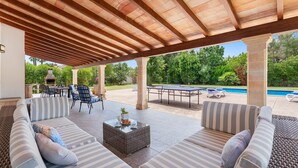 Eine Außenpatio-Terrasse mit überdachter Sitzgelegenheit, einem Pool und einem Grill.