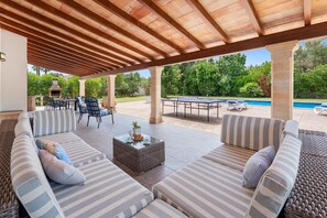 Eine Außenpatio-Terrasse mit überdachter Sitzgelegenheit, einem Pool und einem Grill.