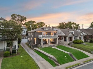 A two-story house with a front porch, a driveway, and a well-maintained lawn. - Swiftie Suite on Music Row | 2BR 2BA | Sleeps 6 (Nashville)