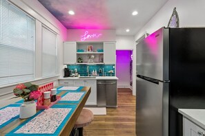 Eine moderne Küche mit einer Neonreklame, Edelstahlgeräten und einer Türkis-farbenen Spritzschutzwand.
