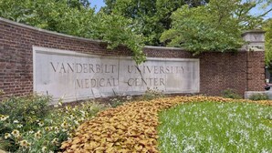 En skylt för Vanderbilt University Medical Center, med en mur av tegelstenar och en välanlagd trädgård i bakgrunden.