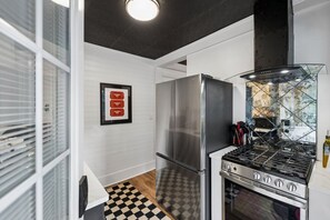 A kitchen with a stainless steel refrigerator, a gas stove, and a black range hood. There is a checkered floor and a framed sign on the wall. - Elvis`s Heartbreak Hotel on Music Row - Sleeps 6 (Nashville)
