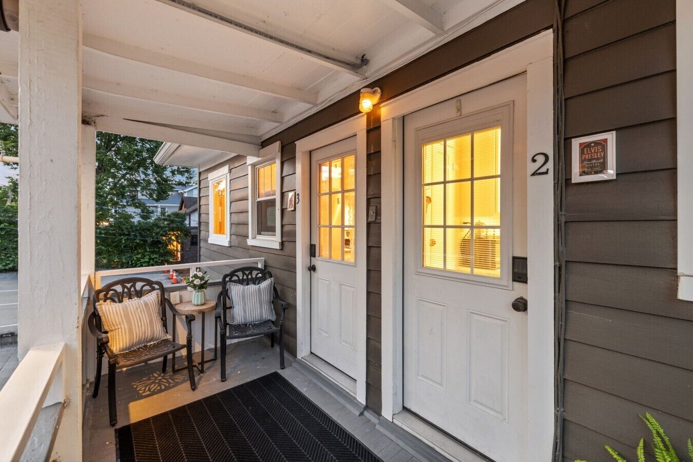 A porch with two doors, a small table with chairs, and a doormat.