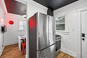 Eine moderne Küche mit einem Edelstahl-Kühlschrank, einem Gasherd und einem Fenster mit Blick ins Grüne.
