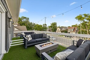 A covered outdoor seating area with a fire pit, a white railing, and a view of the neighborhood. - Johnny Cash Jail House Studio on Music Row (Nashville)