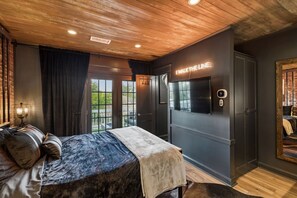 Ein Schlafzimmer mit einem Bett, einem an der Wand befestigten Fernseher und einer Tür mit Fenster.