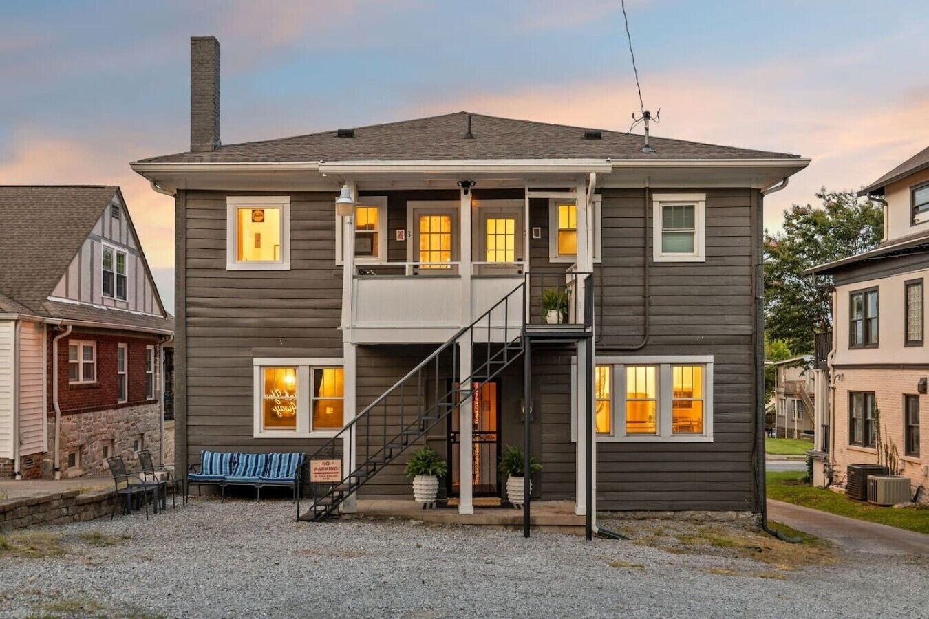 A two-story building with a front porch, a staircase, and a bench.