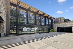 A building with a large glass facade, a sign for Warner Records Nashville, and a parking garage. - Johnny Cash Jail House Studio on Music Row (Nashville)