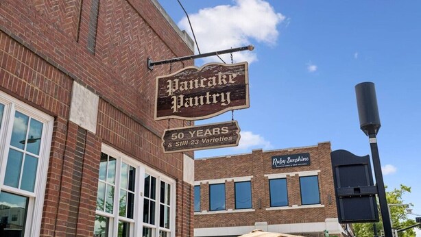 Un edificio in mattoni con un cartello che indica 'Pancake Pantry' e celebra 50 anni di attività e 23 varietà.