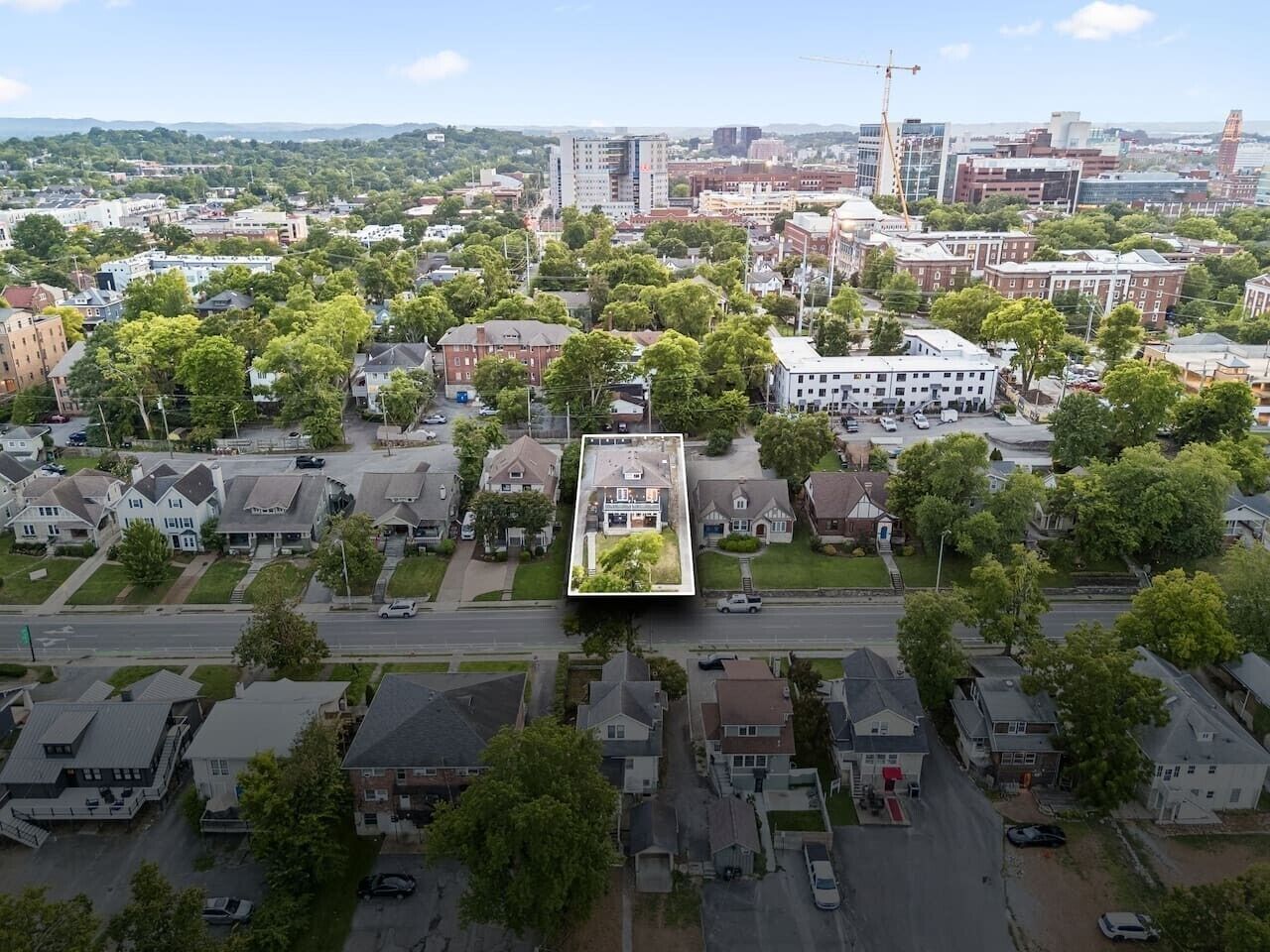 Vista aérea de una zona residencial con casas, calles y una grúa de construcción a lo lejos.