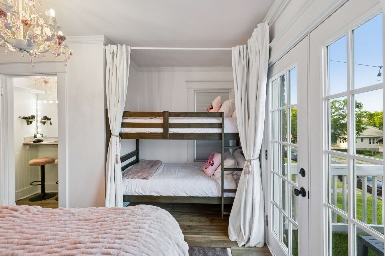 Une chambre avec un lit superposé, une coiffeuse, un miroir et un lustre.