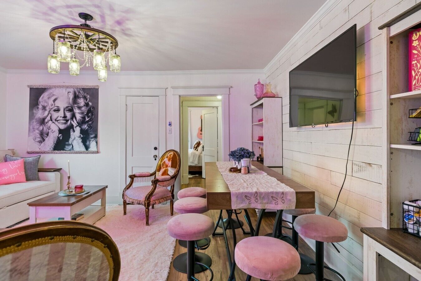 A dining area with a wooden table, pink upholstered chairs, and a chandelier.