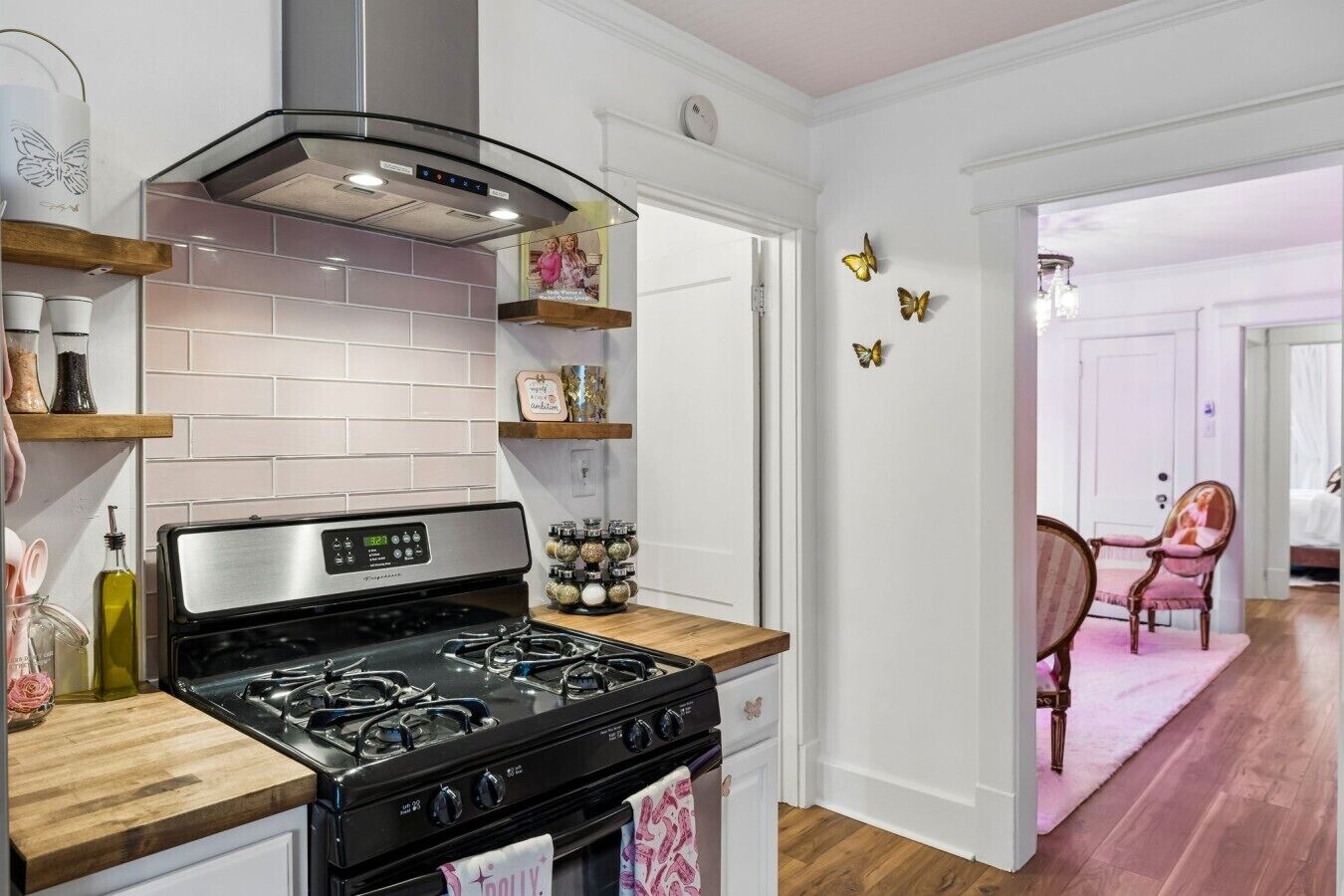 Una cocina moderna con estufa de acero inoxidable, encimeras de madera y salpicadero de azulejos blancos.