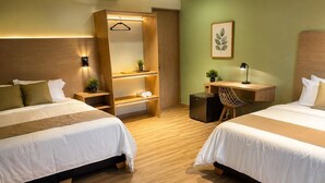 A hotel room with two beds, a desk, a chair, a wardrobe, and a small desk lamp. - Manglea Luxury Hotel (Cartagena)