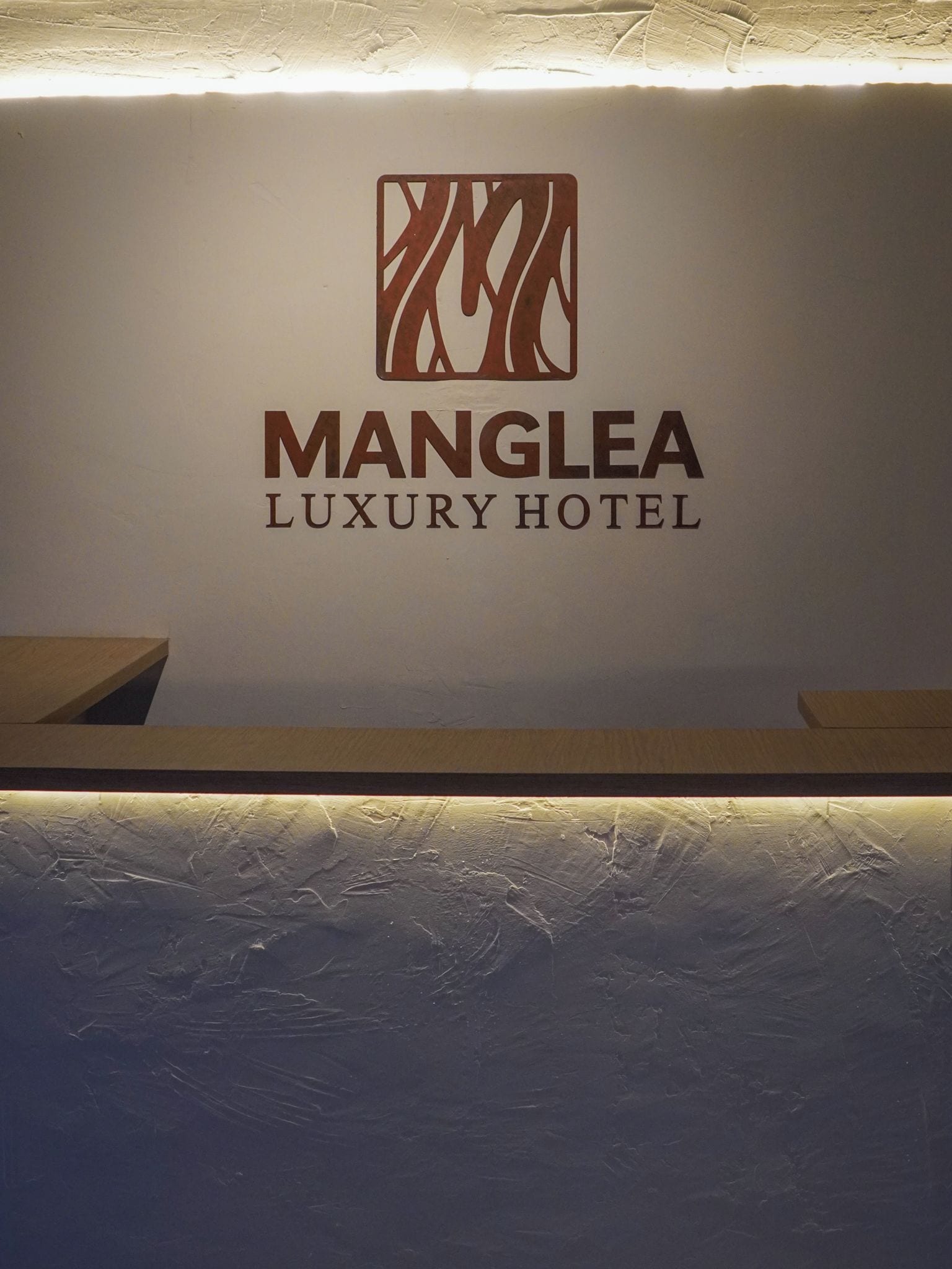A reception desk with a logo and name for Manglea Luxury Hotel.