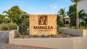 A sign for Manglea Luxury Hotel with a stone facade and a logo. - Manglea Luxury Hotel (Cartagena)