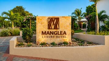 Placa do Manglea Luxury Hotel, fachada em pedra e logotipo.