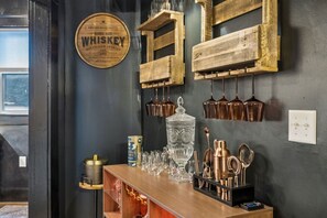 Eine Barbereich mit Whiskey-Schild, Kupferbechern und einer Glasauslage.