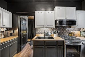 Una cocina moderna con armarios oscuros, una estufa de acero inoxidable y un salpicadero de azulejos.