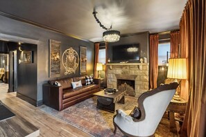 A modern living room with a stone fireplace, leather sofa, and a chandelier. - Tennessee Whiskey Lounge on Music Row - sleeps 6 (Nashville)