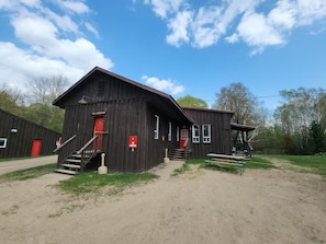 A rustic wooden building with a red door and a staircase leading to the entrance. - Cozy stay at Haliburton Forest. Trails, Wolf Centre, Canopy Tour, 100 lakes! (Dysart and Others)