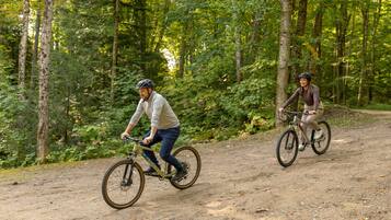 Dois ciclistas em um caminho de terra, cercados por árvores.