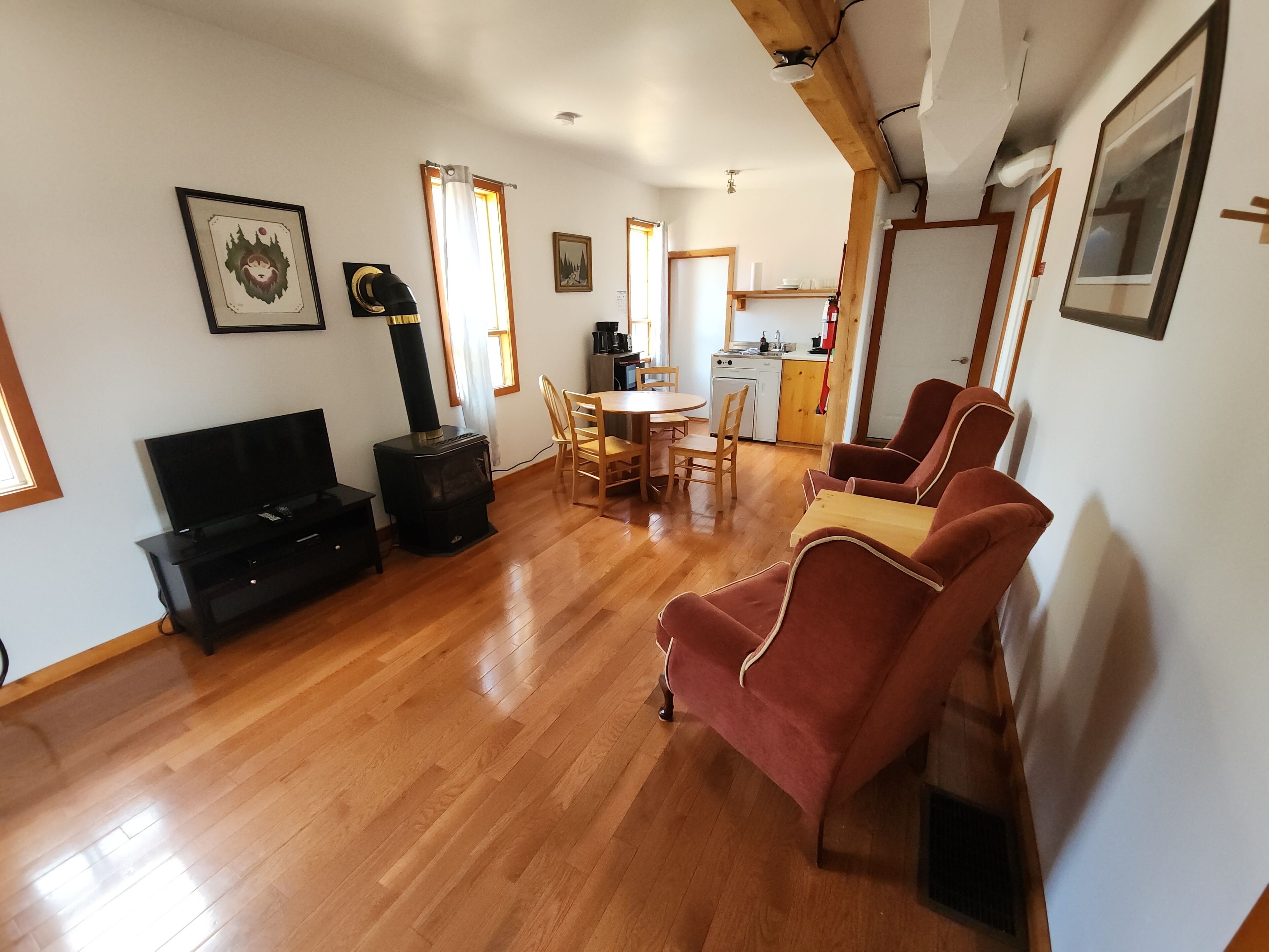 A living room with a TV, a fireplace, a dining table with chairs, and a kitchen area in the background.